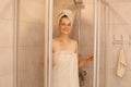 Indoor shot of young woman is getting out of the shower, standing wrapped in white towels, looking at camera with happy facial Royalty Free Stock Photo