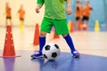 Indoor soccer young player with a soccer ball in a sports hall. Player in green uniform. Sport background. Royalty Free Stock Photo