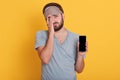 Indoor studio shot of exhausted sleepy bearded young man, looking at camera and covering half of his face with hand, showing his Royalty Free Stock Photo