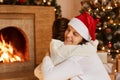 Indoor studio shot of mother and her little daughter hugging in festive room near fireplace and Christmas tree, congratulating Royalty Free Stock Photo