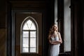 Indoor summer portrait of young pretty cute girl. Beautiful woman posing beside fairytale window inside wood cabinet, scars old ca