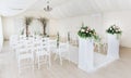 Indoor wedding ceremony with white wedding arch decorated with flowers and big white candles