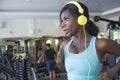 Indoors gym portrait of young attractive black afro American woman with headphones training hard all sweaty at fitness club a trea Royalty Free Stock Photo