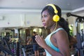 Indoors gym portrait of young attractive black afro American woman with headphones training hard all sweaty at fitness club a trea Royalty Free Stock Photo