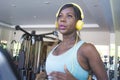 Indoors gym portrait of young attractive black afro American woman with headphones training hard a hard treadmill running workout Royalty Free Stock Photo