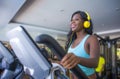 Indoors gym portrait of young attractive and happy black african American woman with headphones training elliptical machine workou