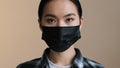 Indoors portrait close facial expression female face asian race woman ill serious girl in black protective medical mask Royalty Free Stock Photo