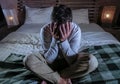 Indoors portrait of young desperate and depressed man at home bedroom sitting on bed sad and confused suffering pain and depressio