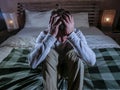 Indoors portrait of young desperate and depressed man at home bedroom sitting on bed sad and confused suffering pain and depressio Royalty Free Stock Photo