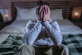 Indoors portrait of young desperate and depressed man at home bedroom sitting on bed sad and confused suffering pain and depressio Royalty Free Stock Photo