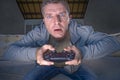 Indoors portrait of young excited and concentrated man at home playing videogames holding controller looking stressed and focused