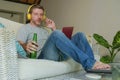 Indoors portrait of young happy relaxed and attractive man sitting at home sofa couch with headset and laptop listening to intern Royalty Free Stock Photo