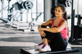 Indoors shot of beautiful girl resting after fitness training. tired young girl sitting break after exercising in gym Royalty Free Stock Photo