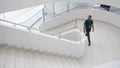 Indoors view of a modern building with men walking on staircase. Media. Beautiful completely white stairs of a business Royalty Free Stock Photo