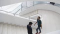 Indoors view of a modern building with men walking on staircase. Media. Beautiful completely white stairs of a business Royalty Free Stock Photo