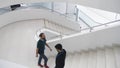 Indoors view of a modern building with men walking on staircase. Media. Beautiful completely white stairs of a business Royalty Free Stock Photo