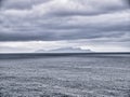 With an induced grain effect on a cold, grey, overcast day, a view across a calm sea to the Shetland island of Foula