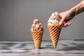 Two scoops of ice cream in waffle cone in female hand on gray background. Royalty Free Stock Photo