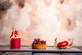 Three fancy desserts with berries on a gray slate board against a mottled pink background Royalty Free Stock Photo