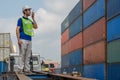 Industrail background of caucasian containers yard and cargo inspector with radio on hand working at containers loading area Royalty Free Stock Photo