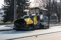 Industrial asphalt paver machine laying fresh asphalt on road construction site on the street. A Paver finisher placing