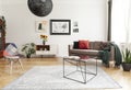 Industrial black coffee table with marble surface and a colorful patchwork chair in a living room interior with mixed style of dec