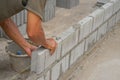 Industrial bricklayer installing brick blocks on construction site, selective focus