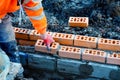 Industrial bricklayer laying bricks on cement mix on construction site. Fighting housing crisis Royalty Free Stock Photo