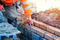 Industrial bricklayer laying bricks on cement mix on construction site. Fighting housing crisis Royalty Free Stock Photo