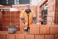 Industrial bricklayer worker placing bricks on cement while building exterior walls Royalty Free Stock Photo