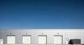 Industrial building with white garage doors under blue sky Royalty Free Stock Photo