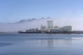 Industrial buildings on harbor being incorporated by fjord fog, Melbu, Norway