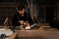 Industrial carpenter worker cutting metal with many sharp sparks at a work bench in a carpentry workshop. Selection focus to