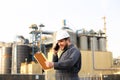 Industrial caucasian engineer talking by VHF walkie talkie and holding papers near factory outside.