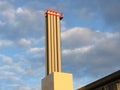 Industrial chimney in front of partly blue, partly polluted sky with dark clouds