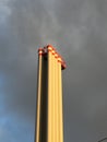 Industrial chimney in front of partly blue, partly polluted sky with dark clouds