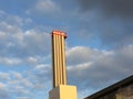 Industrial chimney in front of partly blue, partly polluted sky with dark clouds