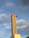 Industrial chimney in front of partly blue, partly polluted sky with dark clouds