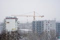 Industrial citycape with unfinished high-rise and crane in winter during snowfall Royalty Free Stock Photo