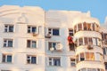 Industrial climber fixed on safety ropes puttying and painting facade of building on sunny day. Bottom view from afar Royalty Free Stock Photo