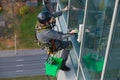 An industrial climber with a green bucket washes windows Royalty Free Stock Photo