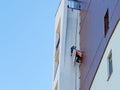 An industrial climber hanging from ropes restores a fragment of a building wall Royalty Free Stock Photo