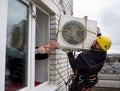 Industrial climber sets the air conditioner on the wall of a block of flats