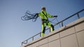 Industrial climber throws rope down from roof of building