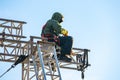 Industrial climber in uniform sitting ts on a building structure