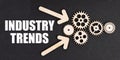 On the black surface, arrows, gears and an inscription - INDUSTRY TRENDS