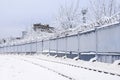 Industrial concrete fence with barbed wire, winter snowy street Royalty Free Stock Photo