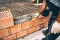 Construction bricklayer worker building walls with bricks, mortar and trowel