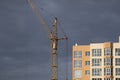 Industrial construction building crane against dark cloudy sky Royalty Free Stock Photo