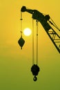 Industrial construction cranes and building silhouettes over sun at sunrise